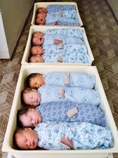 Новорожденные спят в пеленках в роддоме